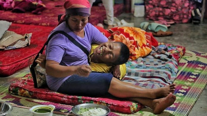 Tingngaipak Vaiphei, the wife of Thangminsiam Vaiphei, feeds their 17-year-old son at a relief camp at St. Peter’s school, Tengnoupal | Praveen Jain | ThePrint