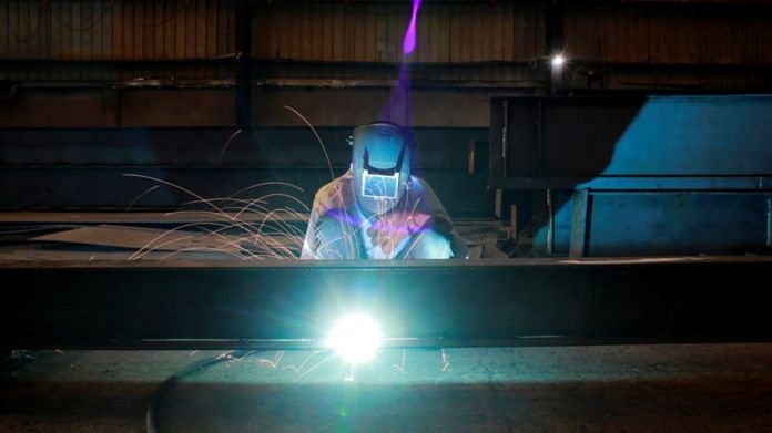 A labourer welds an iron pillar at a building material factory in an industrial area in Dasna, in Uttar Pradesh | Reuters