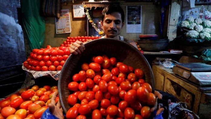 A vendor loads tomatoes in a bag for a customer at a wholesale vegetable market in Mumbai | File Photo: Reuters