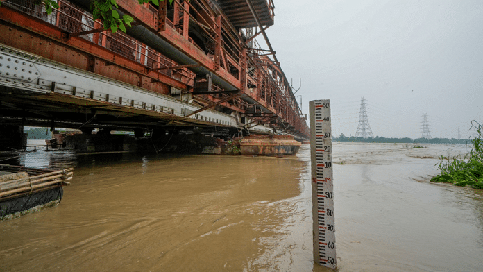 The swollen Yamuna river flows in full spate under the Old Yamuna Bridge (Loha Pul), in New Delhi, on 11 July 2023 | PTI