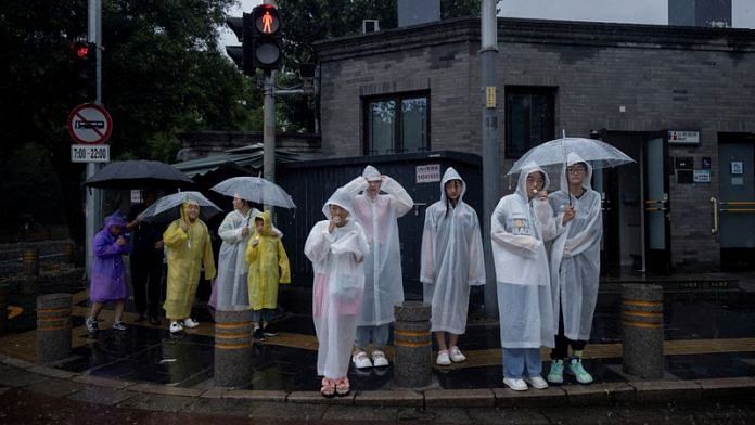 People wear raincoats in a tourist area during heavy rain in Beijing, China, July 30, 2023 | Reuters