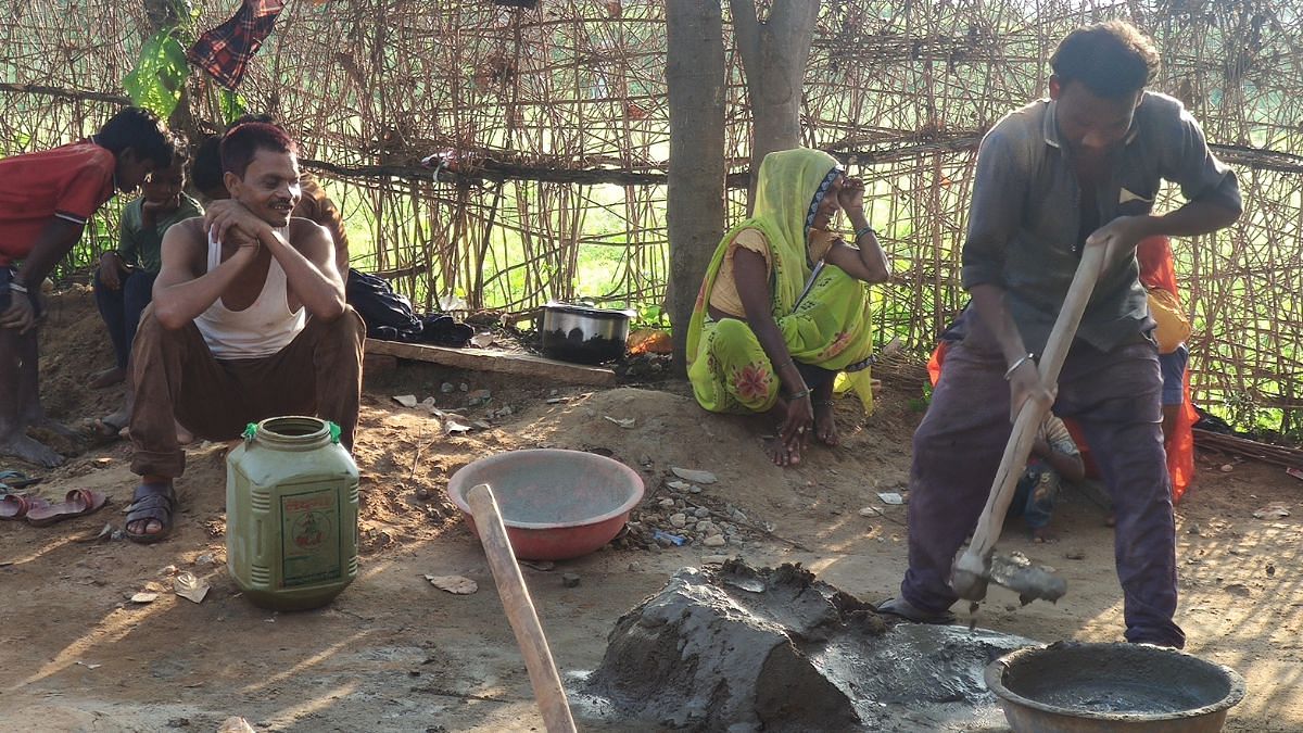 Returning home having completed the day job, Dashmat sits alongside wife Asha as labourers work to construct his puccha house under PM Awas Yojna | Iram Siddique, ThePrint