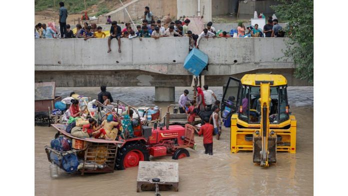 Residents wait to climb on a flyover under construction, after being displaced by the rising water level of river Yamuna after heavy monsoon rains in New Delhi, on July 12, 2023 | Reuters/Adnan Abidi