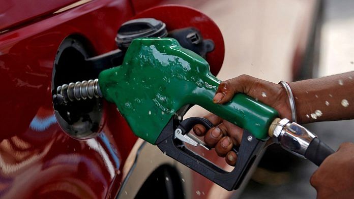 A worker holds a nozzle to pump petrol into a vehicle at a fuel station in Mumbai, India | Reuters