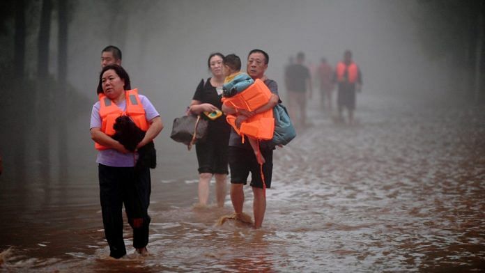 Residents wade through floodwaters following heavy rainfall in Zhuozhou, Hebei province, China | Reuters