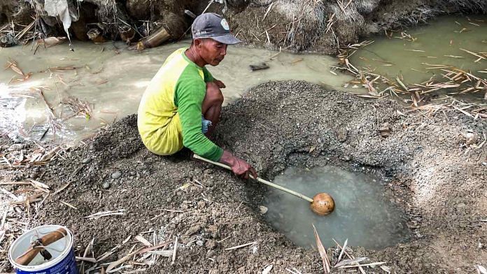 Sunardi, a 52-year-old tobacco farmer, collects murky water for daily needs from a hand-dug well on a dry riverbed, the only remainder of what was once a flowing river as drought strikes in Grobogan regency, Central Java province, Indonesia | Reuters