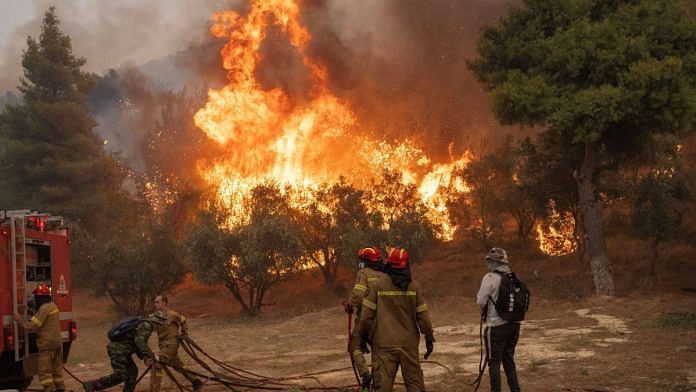 Firefighters and volunteers try to tackle a wildfire burning in the village of Hasia, near Athens, Greece | Reuters