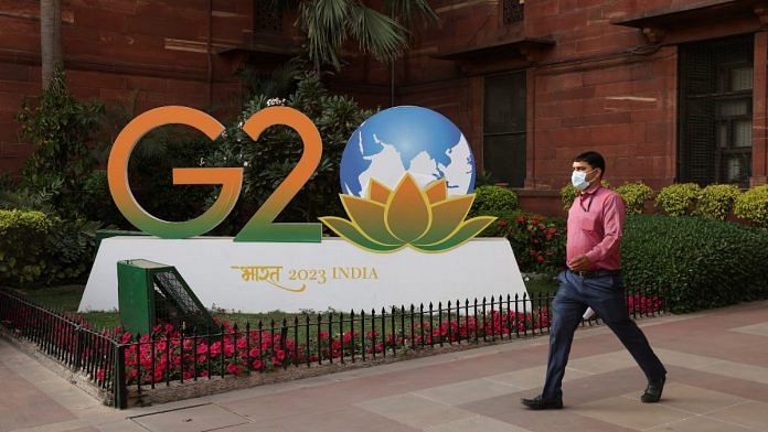 A man walks past a model of G20 logo outside the finance ministry in New Delhi, India | Reuters