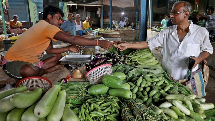 Nikhil Kumar Mondal, 65, a retired school headmaster, buys vegetables from a vendor at a market on the outskirts of Kolkata, India | Reuters