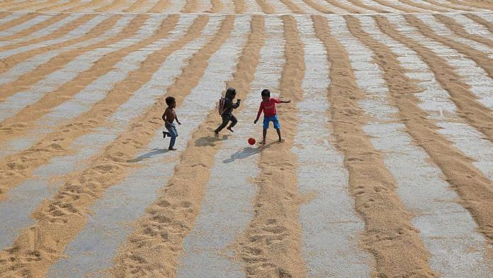 Children play with a ball after rice is spread for drying at a rice mill on the outskirts of Kolkata, India | Reuters