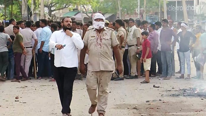A policeman with blood-stains on his shirt at the incident site after a a clash erupted between two groups in Haryana's Nuh on Monday | ANI