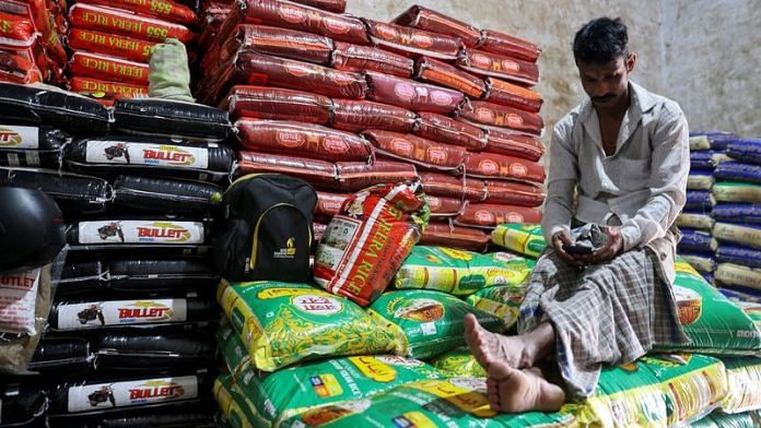 A man sits on rice packets inside a store room, at a wholesale market in Navi Mumbai | Reuters file photo