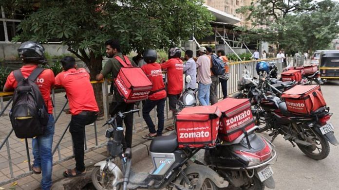 Gig workers wait in line to collect their delivery order outside a mall in Mumbai, India | Reuters