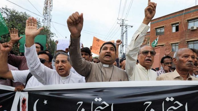 Members of the Christian community chant slogans as they hold a banner to condemn the attacks on churches and houses in Jaranwala town of Faisalabad | Reuters/Fayaz Aziz