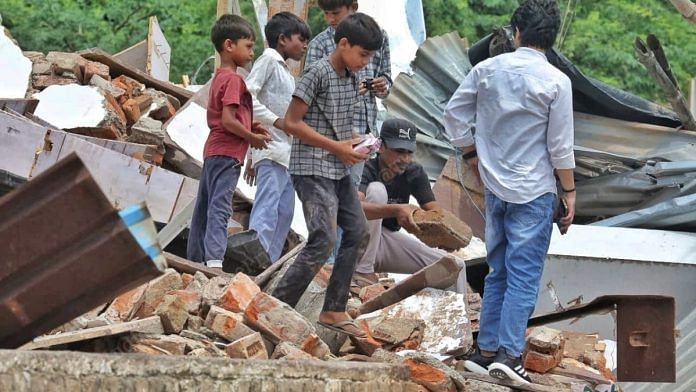 Sufiyan Ahmed (sitting) rummages through the rubble of their demolished chemist shop with the help of family | Praveen Jain | ThePrint