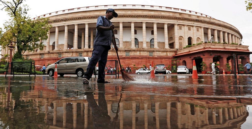 Parliament building is reflected in a puddle after the rain as a man sweeps the water in New Delhi, India July 20, 2018 | Reuters