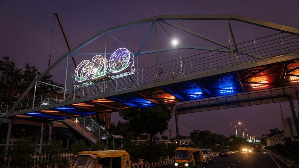 Traffic moves past under a G20 logo installed on a pedestrian bridge in front of the main venue of the summit in New Delhi, India | Reuters