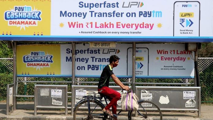 A man rides a bicycle past a bus stop with Paytm advertisements in Mumbai, India | Reuters
