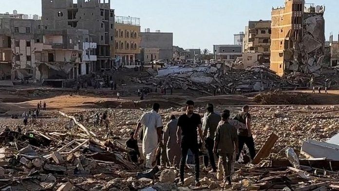 People walk through debris after a powerful storm and heavy rainfall hit Libya, in Derna, Libya, on 12 September 2023 | ALI M. BOMHADI/via Reuters