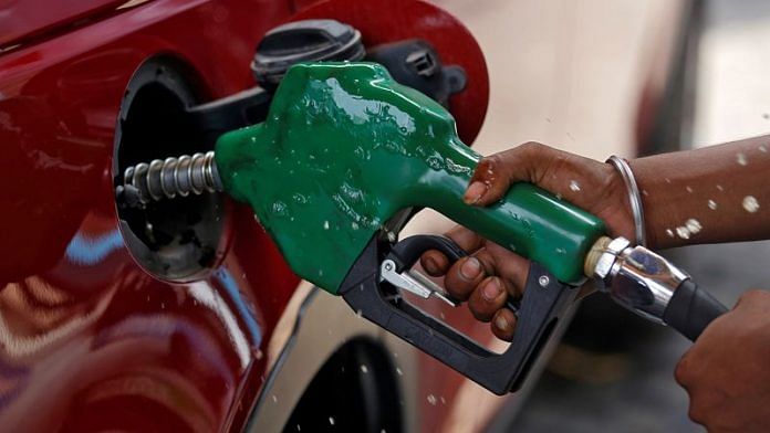 A worker holds a nozzle to pump petrol into a vehicle at a fuel station in Mumbai | Reuters