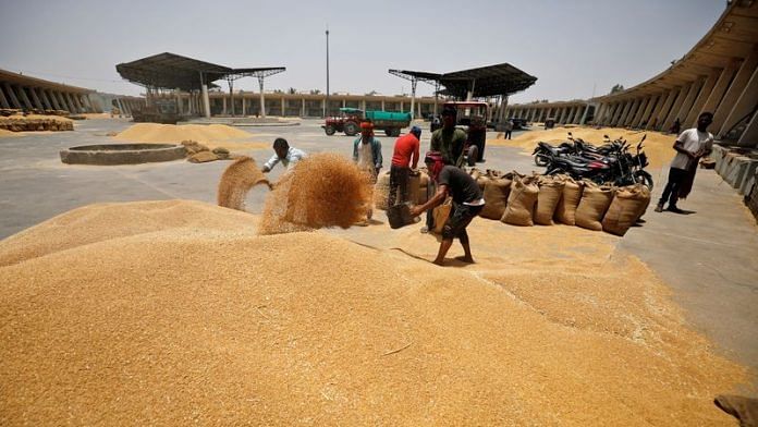 Workers fill sacks with wheat at the market yard of the Agriculture Product Marketing Committee (APMC) on the outskirts of Ahmedabad | Reuters
