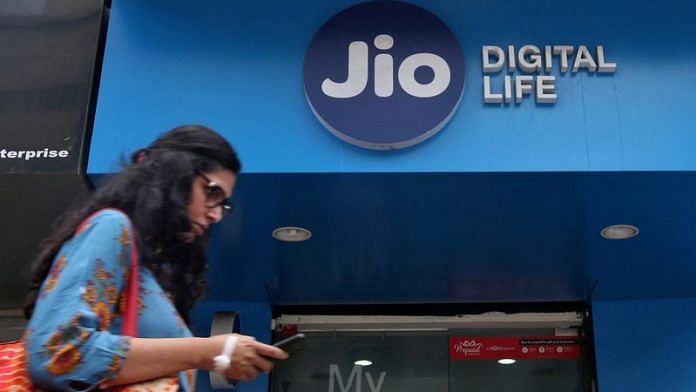 A woman checks her mobile phone as she walks past a mobile store of Reliance Industries' Jio telecoms unit in Mumbai | Reuters