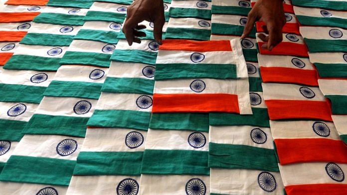 An employee of Assam Khadi and Village Industries Board dries clothes after manually screen printing the Ashok Chakra symbol during the process of making Indian national flags | ANI