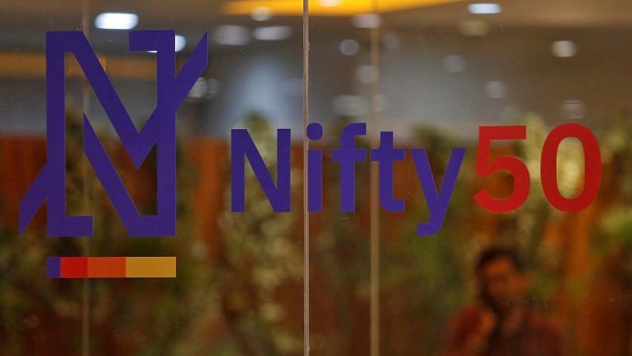 A man speaks on his mobile phone past a new brand identity for Nifty Indices inside the National Stock Exchange (NSE) building in Mumbai, India | Reuters