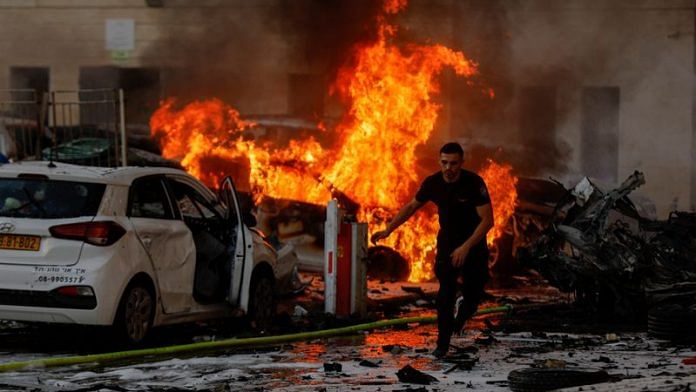 A man runs on a road as fire burns after rockets were launched from the Gaza Strip, in Ashkelon, Israel October 7, 2023. REUTERS/Amir Cohen