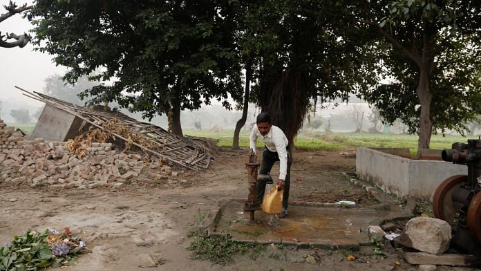 Totaram Maurya,45, a construction worker, fills water in a container using a handpump near his house on the Yamuna floodplains on a smoggy morning in New Delhi, India | Reuters