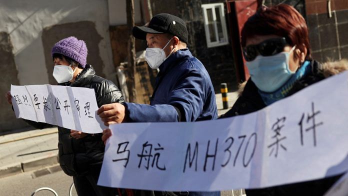 Family members hold signs as they speak to the media following a court hearing on compensation for those who lost their loved ones on the Malaysia Airlines flight MH370 that went missing in 2014, in Beijing, China | Reuters