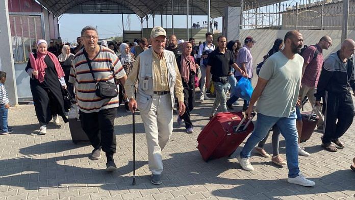 Palestinians with dual citizenship walk at the Rafah border crossing with Egypt, on 1 November 2023 | Reuters