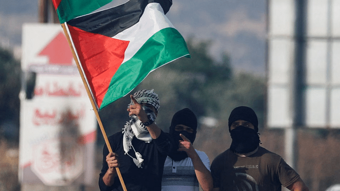 Palestinians hold the Palestinian flag during a protest over tensions in Jerusalem's Al-Aqsa Mosque, at Huwara checkpoint, near Nablus in the Israeli-occupied West Bank May 29, 2022. REUTERS/Raneen Sawafta