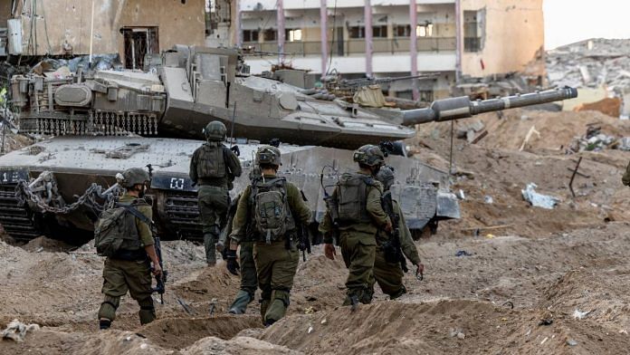 Israeli soldiers walk through rubble, amid the ongoing ground invasion against Palestinian Islamist group Hamas in the northern Gaza Strip | Reuters