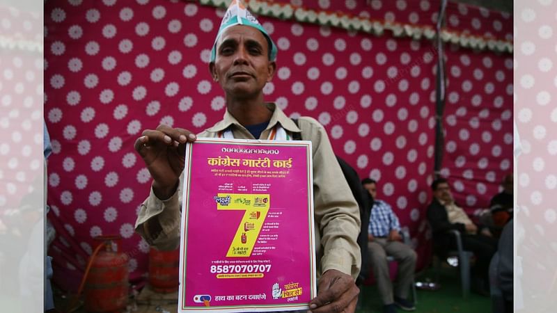A congress supporter holds up a poster of party's 'Guarantee Card' for Rajasthan | Photo: Manisha Mondal, ThePrint 
