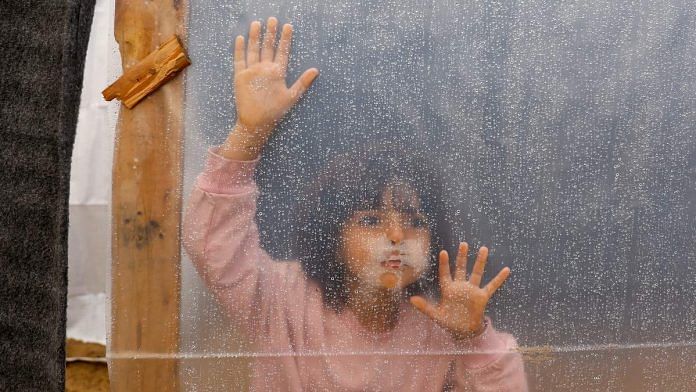 A displaced Palestinian girl looks through a plastic sheet covering a shelter at a tent camp, following a rainfall in Khan Younis in the southern Gaza Strip | Reuters