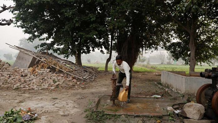 Totaram Maurya, 45, a construction worker, fills water in a container using a handpump near his house on the Yamuna floodplains in New Delhi | Reuters
