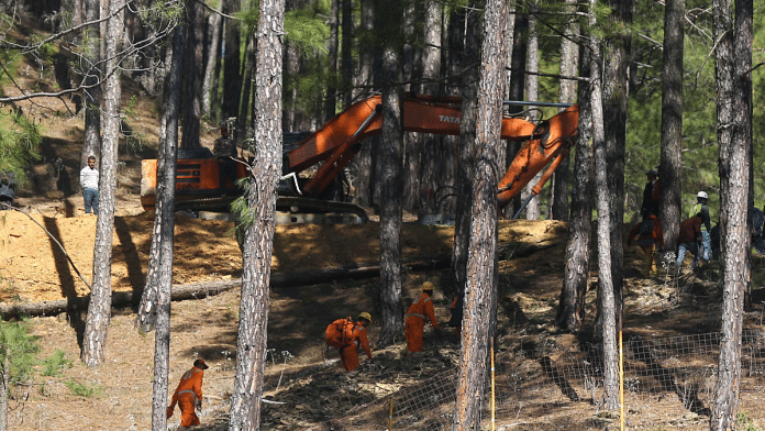 A JCB prepares makeshift road to faciliate construction of a platform for vertical drilling in order to rescue the workers trapped inside the collapsed tunnel in Uttarkashi | Suraj Singh Bisht | ThePrint