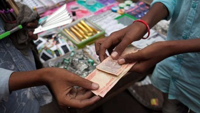 A vendor hands Indian rupee notes to a customer at a stall in Chauta Bazaar in Surat, Gujarat (representational image) | Photo: Karen Dias | Bloomberg