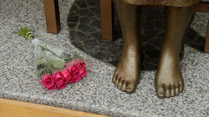 A bouquet lays alongside a statue commemorating Korean 