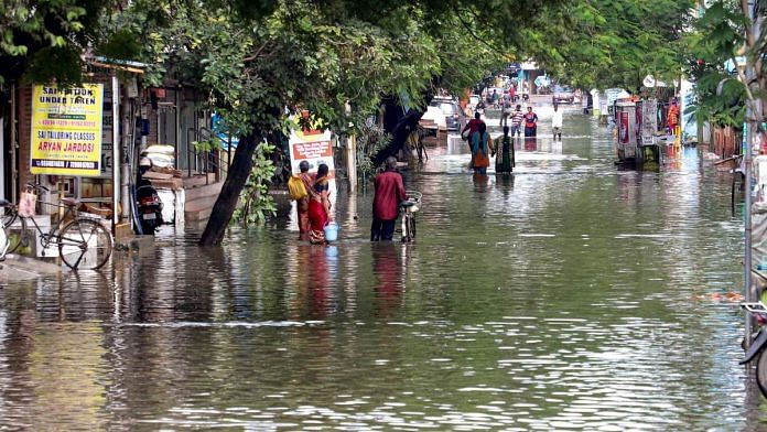 Locals wade through a waterlogged street after heavy rain in Chennai, on 30 Nov 2023 | PTI