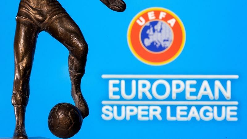 A metal figure of a football player with a ball is seen in front of the words "European Super League" and the UEFA logo in this illustration | Reuters