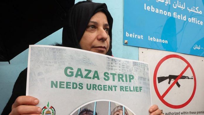 A Palestinian woman holds a placard during a protest in front of the United Nations Palestinian aid agency UNRWA's building in Beirut, Lebanon January 30, 2024 | Reuters