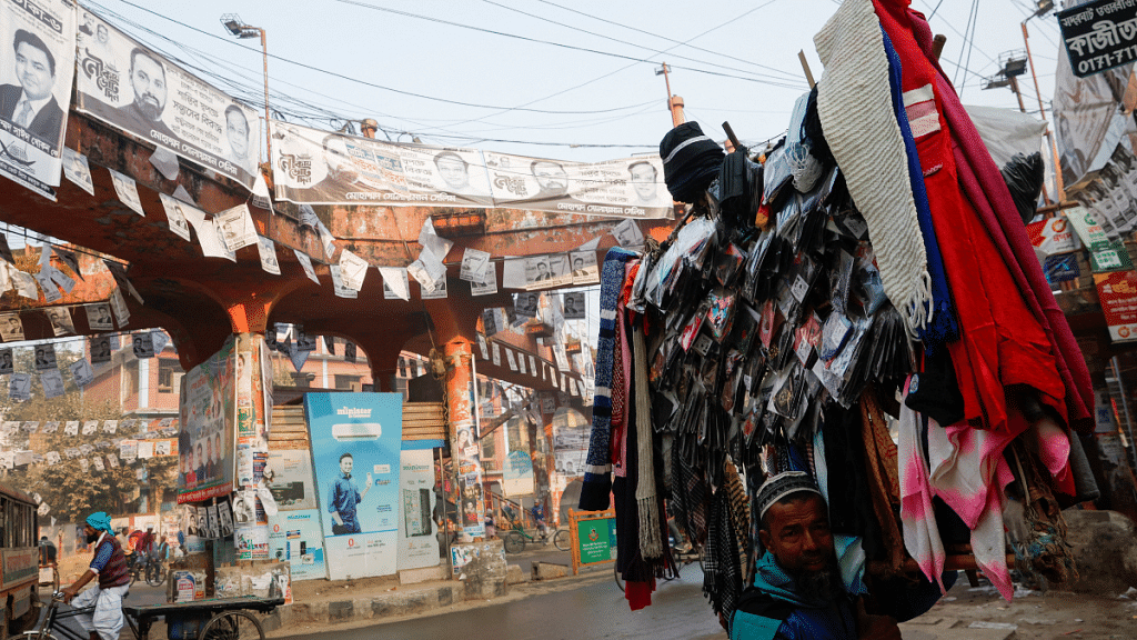 A man carries winter caps and scarves to sell in Dhaka, as election campaign posters hang over a street ahead of the Bangladesh general election | Reuters