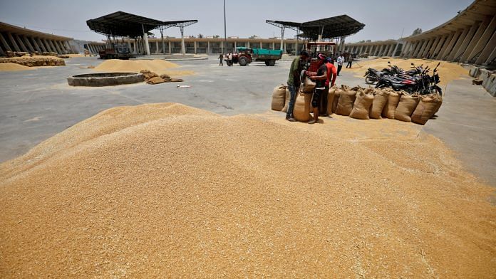 Workers fill sacks with wheat at the market yard of the Agriculture Product Marketing Committee (APMC) on the outskirts of Ahmedabad, India | Reuters