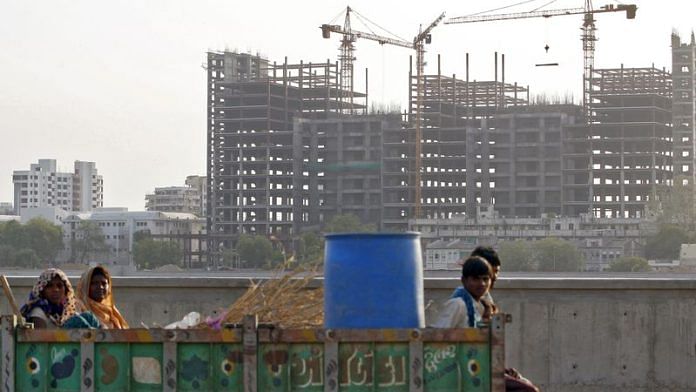Labourers travel in a tractor trolley past hospital buildings under construction, after finishing their day's work, in Ahmedabad, India, May 27, 2015. REUTERS/Shailesh Andrade/File Photo