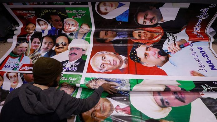 A worker receives panaflex posters from a printer, to be used for campaigns of political parties, at a workshop ahead of general elections in Karachi, Pakistan | Reuters file photo