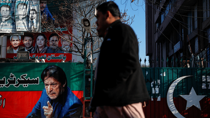 People walk past a banner with a picture of the former Prime Minister Imran Khan outside the party office of Pakistan Tehreek-e-Insaf (PTI), a day after the general election, in Lahore, Pakistan, February 9, 2024 | Navesh Chitrakar | Reuters