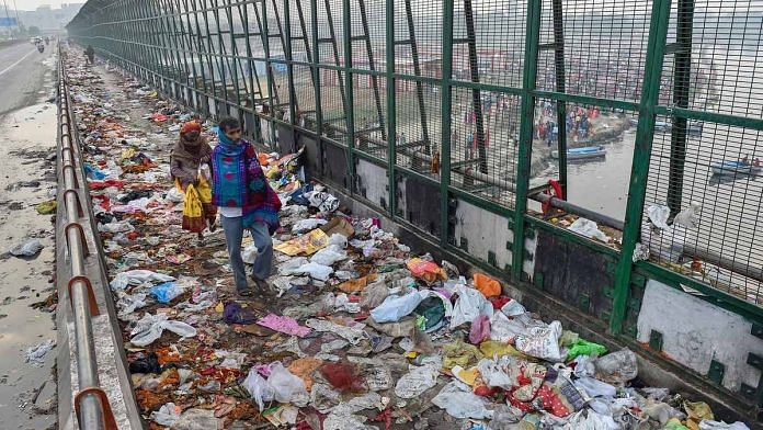 Pedestrians walk over plastic bags scattered on the pavement along Geeta Colony Setu over the River Yamuna, in New Delhi | PTI Photo/ Manvender Vashist