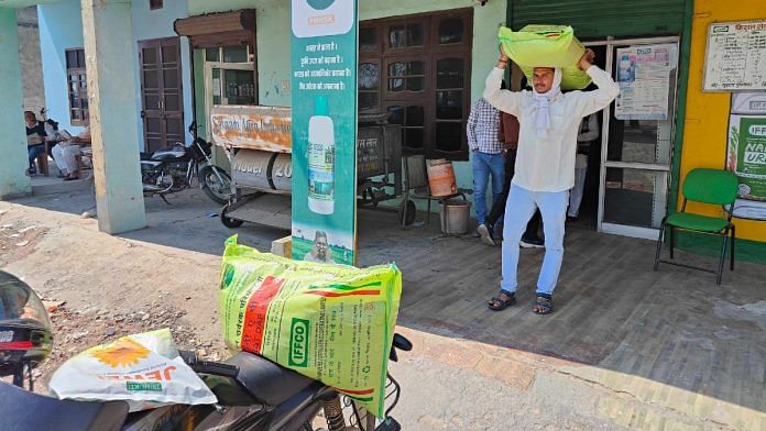 Farmer Balwinder Singh carries a bag of granular urea to his motorcycle, purchased from the Pradhan Mantri Kisan Samriddhi Kendra in Karnal, Haryana | TCA Sharad Raghavan | ThePrint